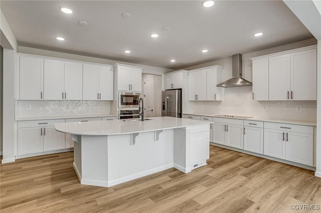 7127 Braxton Ct, Ladysmith, VA 22546 - kitchen featuring wall chimney exhaust hood, appliances with stainless steel finishes, a kitchen island with sink, light countertops, and white cabinetry