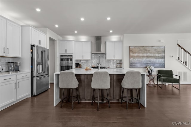 10109 Hollythorne Ln, Mechanicsville, VA 23116 - kitchen with appliances with stainless steel finishes, wall chimney exhaust hood, tasteful backsplash, a center island with sink, and light countertops