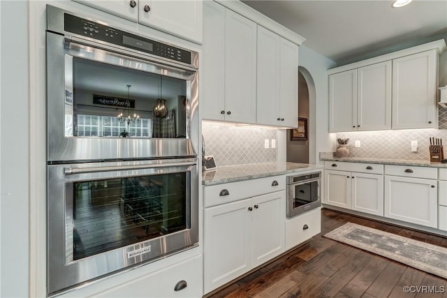 5025 Ellis Meadows Ct, Glen Allen, VA 23059 - kitchen with double oven, arched walkways, white cabinets, dark wood-type flooring, and decorative backsplash