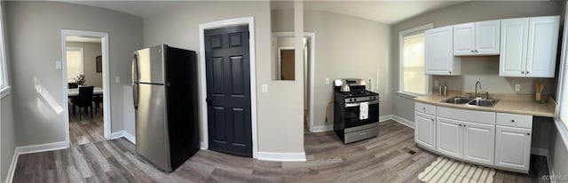 1883 Fairfax St, Petersburg, VA 23805 - kitchen featuring appliances with stainless steel finishes, light wood finished floors, white cabinetry, light countertops, and vaulted ceiling