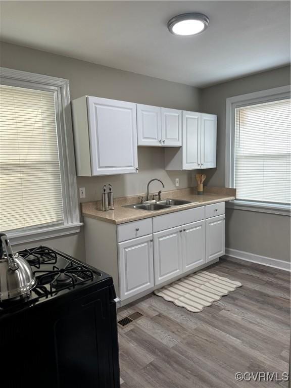 1883 Fairfax St, Petersburg, VA 23805 - kitchen featuring black range with gas cooktop, white cabinets, light countertops, and light wood-type flooring