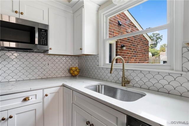 6213 Monument Ave, Richmond, VA 23226 - kitchen featuring stainless steel microwave, white cabinetry, backsplash, and light stone countertops