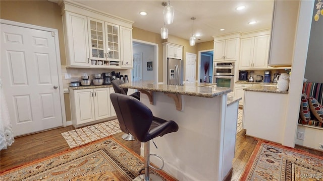 2024 Rockstone Pl, Henrico, VA 23238 - kitchen with stainless steel appliances, light wood-style floors, a center island, a kitchen breakfast bar, and light stone countertops