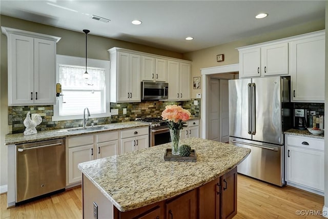 7413 Settlers Ridge Ct, Henrico, VA 23231 - kitchen with appliances with stainless steel finishes, backsplash, white cabinetry, a kitchen island, and light wood finished floors