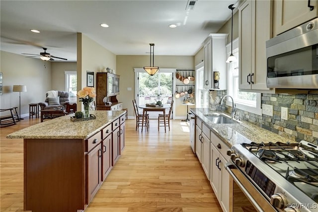 7413 Settlers Ridge Ct, Henrico, VA 23231 - kitchen featuring appliances with stainless steel finishes, light wood finished floors, decorative backsplash, hanging light fixtures, and light stone counters