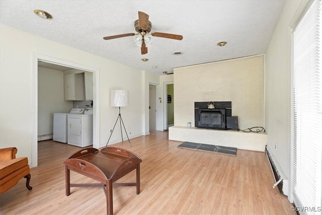 1415 New Market Rd 1411, Henrico, VA 23231 - living room featuring independent washer and dryer, light wood-type flooring, ceiling fan, a baseboard heating unit, and a textured ceiling