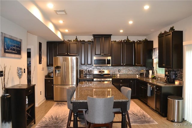 4331 Ganymede Dr, Chester, VA 23831 - kitchen with appliances with stainless steel finishes, dark stone countertops, light wood-type flooring, backsplash, and a breakfast bar