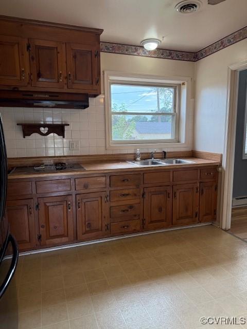 4002 Crystalwood Ln, Henrico, VA 23294 - kitchen with under cabinet range hood, black cooktop, brown cabinetry, and decorative backsplash