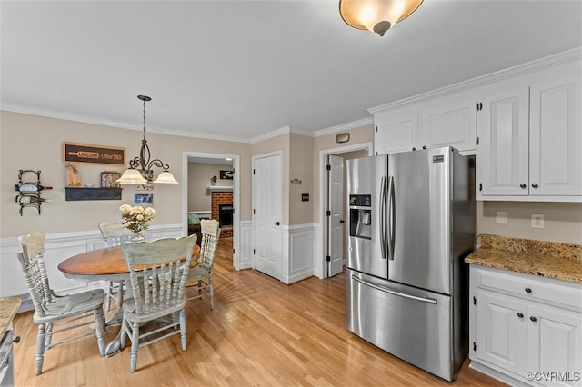 6003 Lansgate Rd, Midlothian, VA 23112 - dining room featuring crown molding, light wood-style flooring, a wainscoted wall, a fireplace, and a chandelier