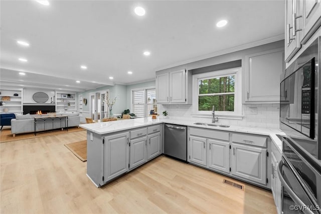 13219 Lauren Ln, Midlothian, VA 23114 - kitchen with gray cabinets, a lit fireplace, a peninsula, stainless steel appliances, and tasteful backsplash
