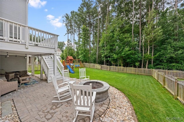 18007 Twin Falls Ln, Moseley, VA 23120 - fenced backyard featuring a patio area, a fire pit, a playground, a wooden deck, and view of wooded area