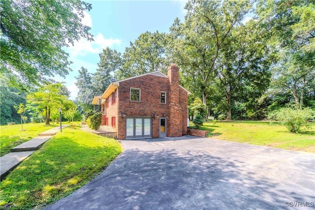 1020 Challis Ln, Sandston, VA 23150 - view of side of property with brick siding, a chimney, a lawn, driveway, and french doors