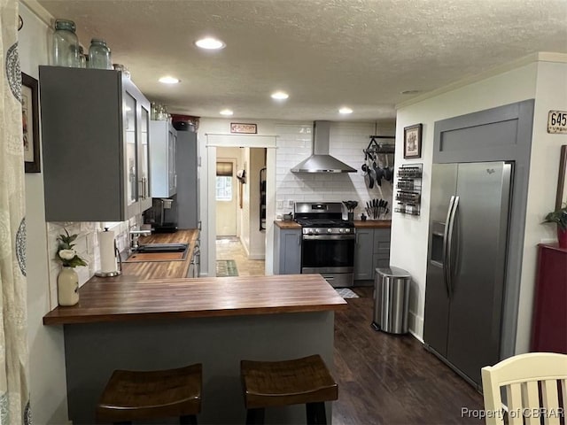 102 Mechams Cove Rd, Topping, VA 23169 - kitchen featuring butcher block counters, appliances with stainless steel finishes, wall chimney range hood, decorative backsplash, and gray cabinetry