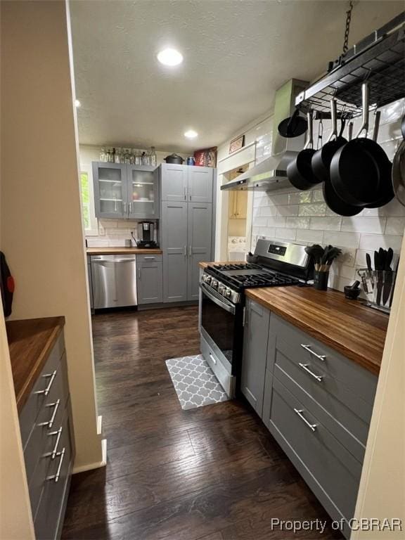 102 Mechams Cove Rd, Topping, VA 23169 - kitchen featuring butcher block counters, stainless steel appliances, gray cabinetry, wall chimney exhaust hood, and backsplash