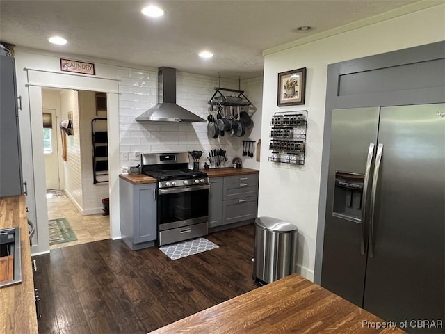 102 Mechams Cove Rd, Topping, VA 23169 - kitchen with wood counters, appliances with stainless steel finishes, wall chimney range hood, dark wood finished floors, and gray cabinetry