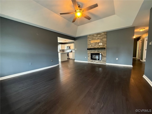 9903 Bethwood Dr, Fredericksburg, VA 22407 - unfurnished living room featuring a ceiling fan, dark wood-style flooring, a tray ceiling, and a fireplace