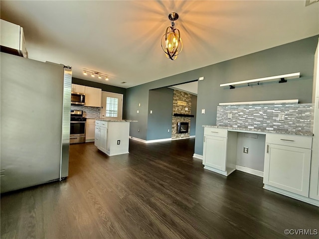 9903 Bethwood Dr, Fredericksburg, VA 22407 - kitchen featuring appliances with stainless steel finishes, decorative backsplash, a stone fireplace, dark wood finished floors, and white cabinets