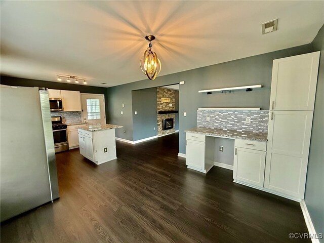 9903 Bethwood Dr, Fredericksburg, VA 22407 - kitchen with appliances with stainless steel finishes, tasteful backsplash, white cabinetry, and a stone fireplace