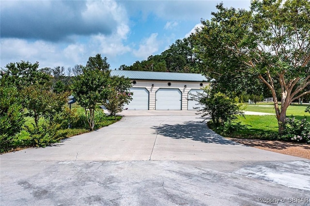 744 Possum Point Rd, Port Haywood, VA 23109 - view of front of house with concrete driveway, a garage, a front yard, and a metal roof