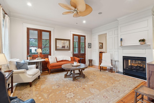 living room with crown molding, a multi sided fireplace, french doors, and light wood-type flooring