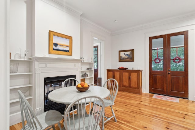 dining area with french doors, ornamental molding, and light hardwood / wood-style flooring