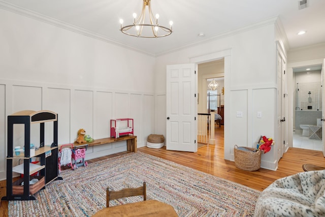 recreation room featuring an inviting chandelier, crown molding, and light hardwood / wood-style floors