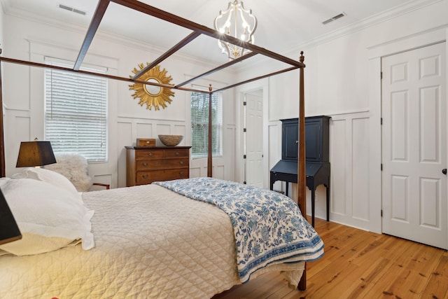 bedroom with ornamental molding, wood-type flooring, and a notable chandelier