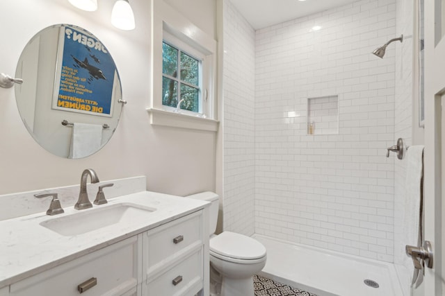 bathroom featuring vanity, tiled shower, and toilet