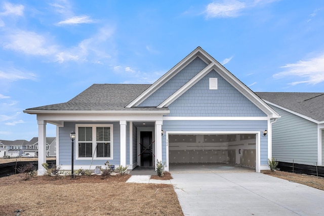 view of front of house with a porch, driveway, a garage, and roof with shingles