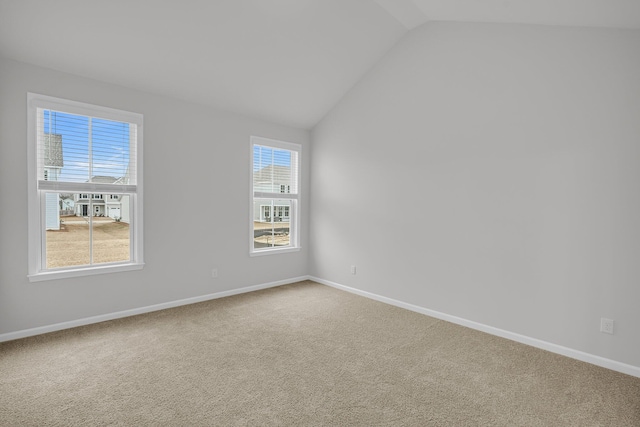 carpeted spare room featuring baseboards and lofted ceiling