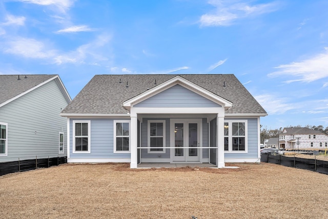 back of property with a shingled roof, a sunroom, fence private yard, and a lawn