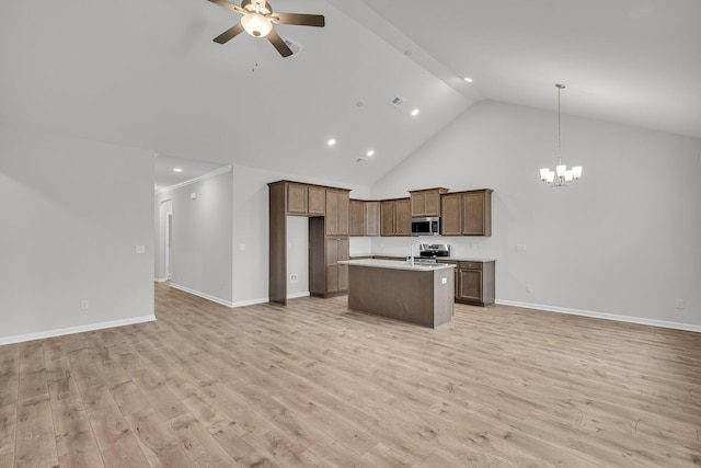 kitchen featuring ceiling fan with notable chandelier, open floor plan, light countertops, a kitchen island with sink, and appliances with stainless steel finishes