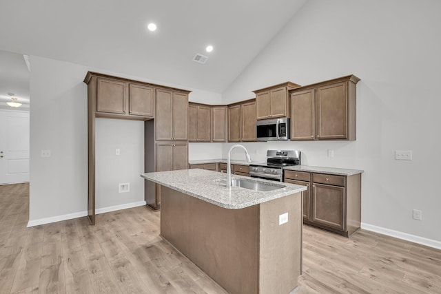 kitchen featuring light wood finished floors, visible vents, a sink, a center island with sink, and stainless steel appliances