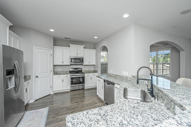 kitchen featuring dark wood-type flooring, stainless steel appliances, sink, light stone countertops, and white cabinets