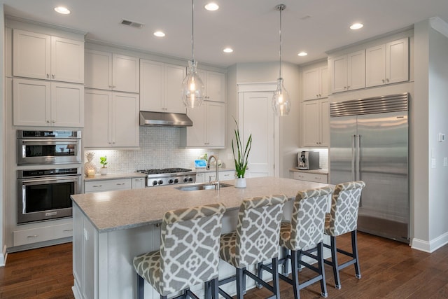 kitchen with decorative light fixtures, white cabinetry, sink, a kitchen breakfast bar, and stainless steel appliances