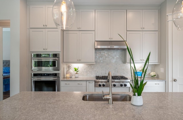 kitchen with decorative backsplash, white cabinets, and appliances with stainless steel finishes