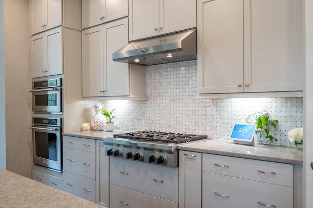 kitchen featuring light stone counters, backsplash, and stainless steel appliances