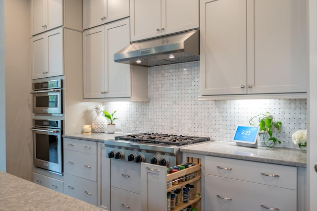 kitchen featuring light stone countertops, backsplash, and stainless steel appliances