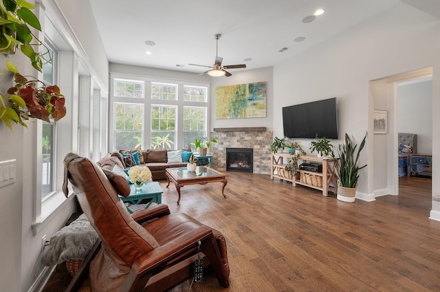 living room with hardwood / wood-style flooring, ceiling fan, and a fireplace