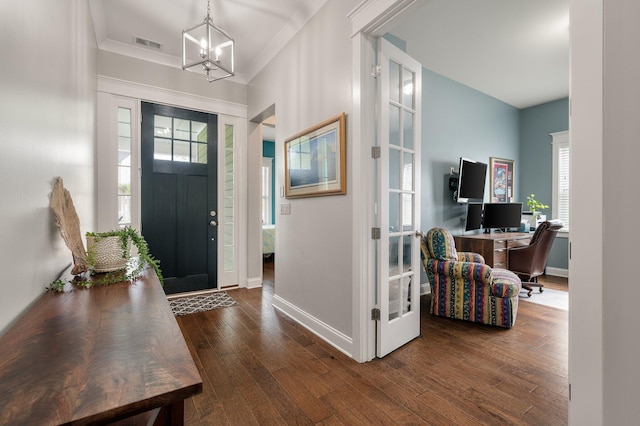 entrance foyer with crown molding, dark wood-type flooring, an inviting chandelier, and french doors