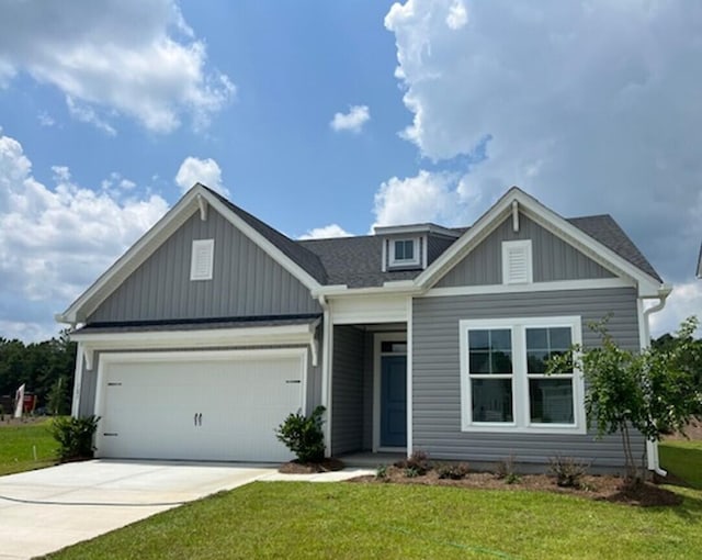 view of front of house with board and batten siding, a shingled roof, a front lawn, a garage, and driveway