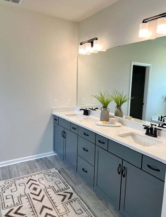 full bath with wood tiled floor, double vanity, and a sink