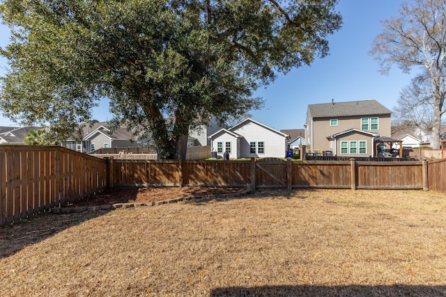 view of yard featuring a residential view, a fenced backyard, and a gate