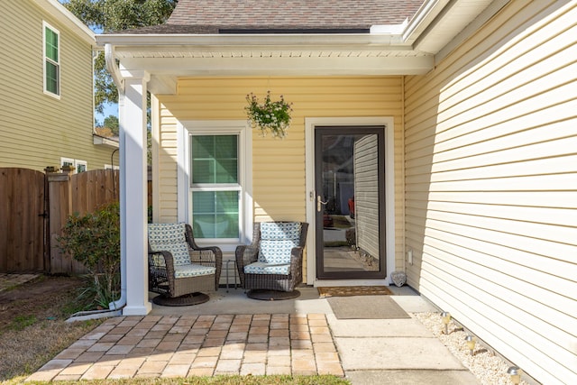 property entrance with roof with shingles and fence