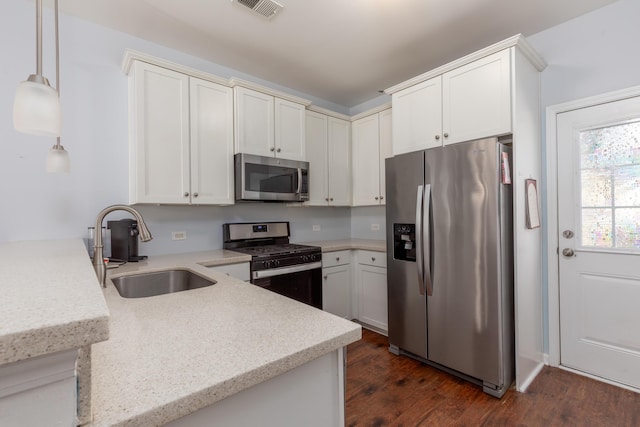 kitchen with visible vents, a sink, appliances with stainless steel finishes, a peninsula, and dark wood-style flooring