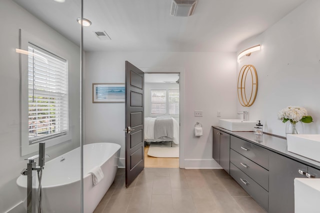 ensuite bathroom featuring a soaking tub, visible vents, a sink, and double vanity