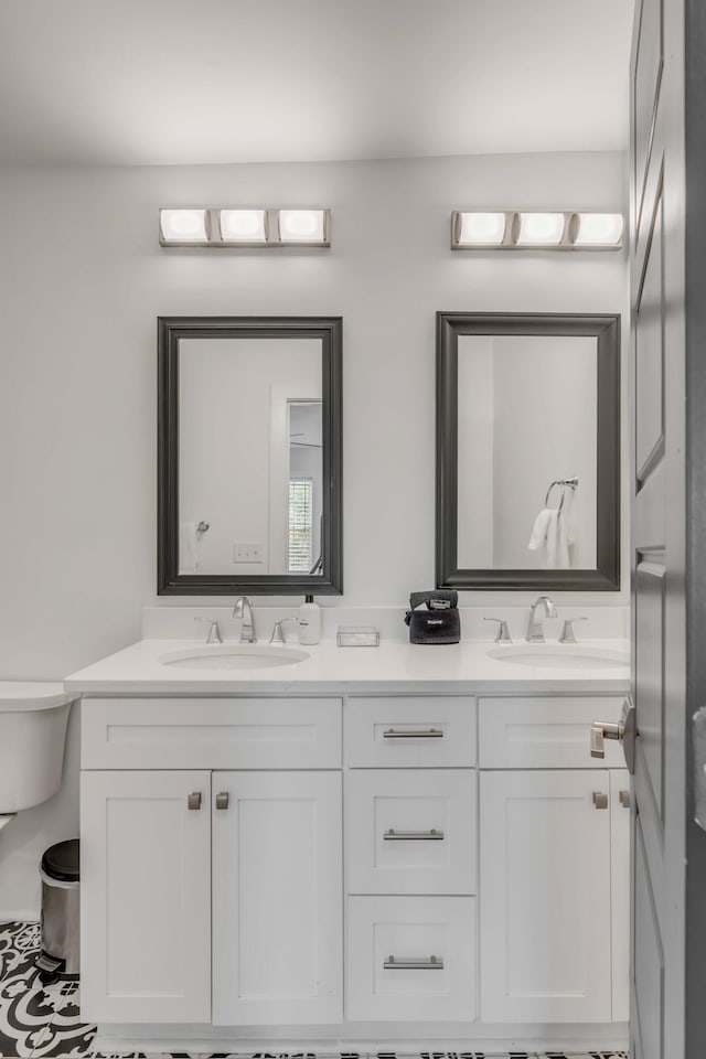 bathroom with double vanity, a sink, and toilet