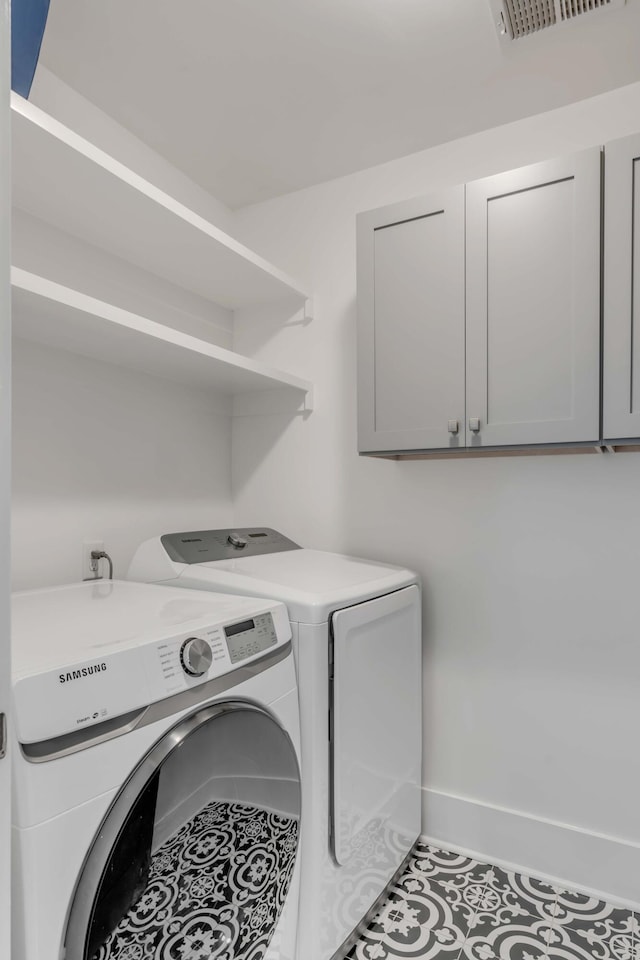 laundry area with visible vents, tile patterned flooring, washing machine and dryer, and cabinet space