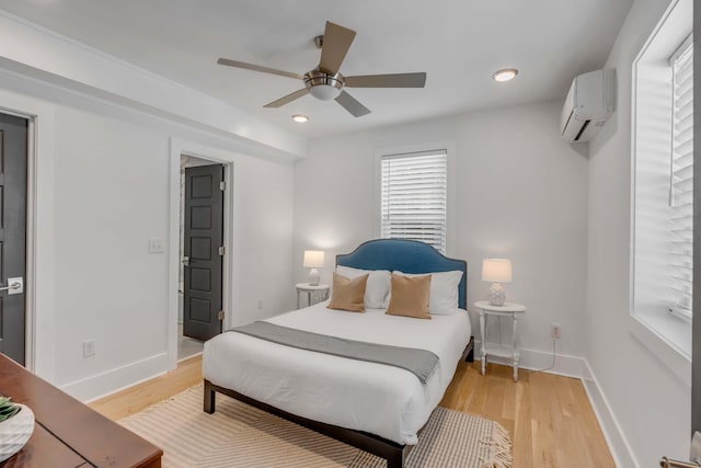 bedroom featuring a ceiling fan, light wood-type flooring, baseboards, and a wall mounted AC