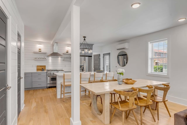 dining space with light wood-style flooring, baseboards, and a wall mounted AC